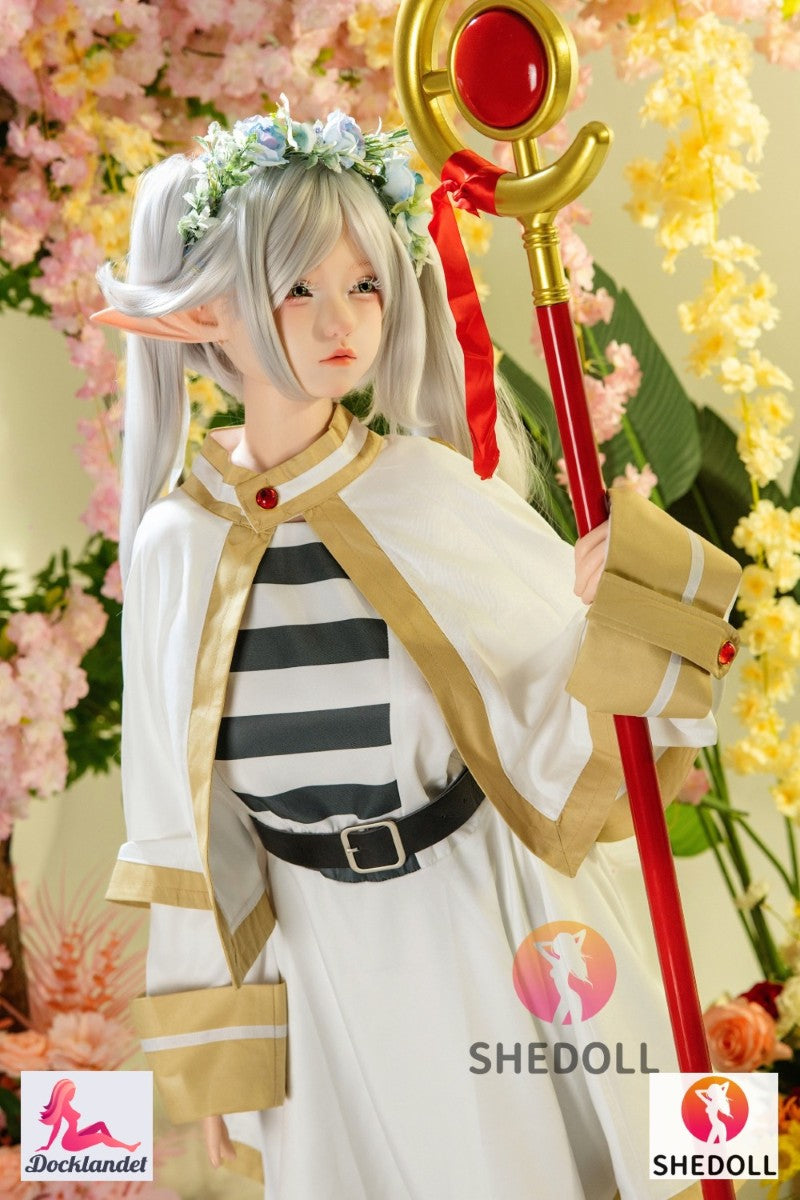 Frieren is a premium cosplay doll inspired by the popular character from Frieren: Beyond Journey's End. Šis 155 cm ilgio silikoninis modelis nuo SHEDOLL combines a sleek, elf-like aesthetic with a plump G-cup, realistic skin feel and a modern EVO skeleton for natural poses. The character Frieren is a 1000 year old elven mage and demon hunter, also called "Frieren the Slayer", who won the hearts of many anime fans with his charming socially incompetent style. Tai šiuo metu labai populiarus personažas